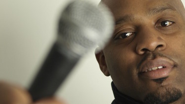 Comedian Victor Daniels posing with microphone.