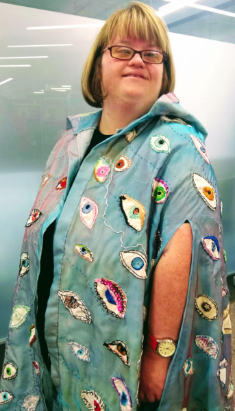 A member of East London Textile Arts (ELTA) wearing a decorative cloak.