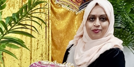 Farzana Hakim stands before a colourful backdrop.