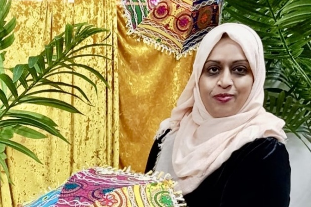 Farzana Hakim stands before a colourful backdrop.